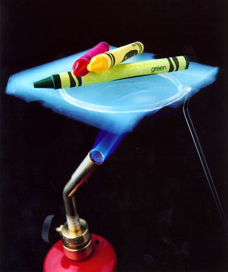 얇은 에어로젤 판 위에 크레파스를 올려 두고 아래에서 불꽃을 쏜 모습이에요. 판 아래는 불꽃이 닿는데 위의 크레파스는 녹지 않았어요. 연구실에서 전문가가 한 실험이에요.